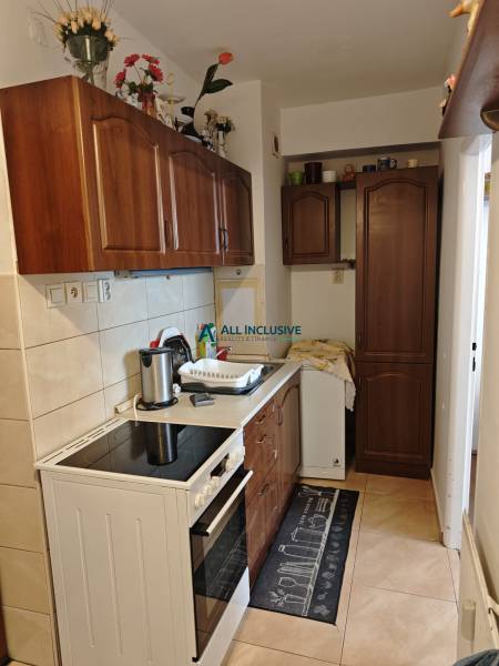 Küche in einer 2-Zimmer-Wohnung mit Herd, Spüle und Holzschränken.