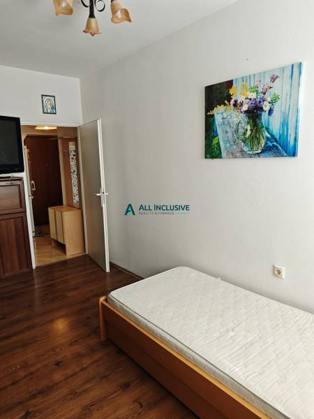 Ein einfaches Zimmer mit einem Bett und einem Bild in einer Zweizimmerwohnung.