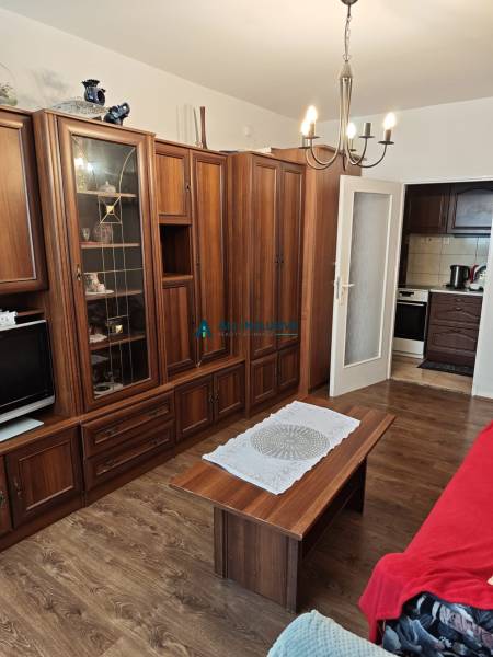 Wohnzimmer mit einer Holzwand-Einheit, einem Kronleuchter und einem Tisch in einer Zweizimmerwohnung.