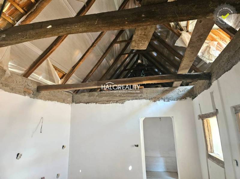 Innenraum eines Einfamilienhauses mit freiliegenden Holzdachbalken und weiß verputzten Wänden.