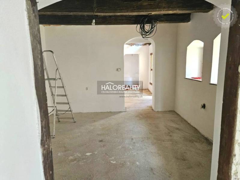 Unvollendetes Interieur in einem Einfamilienhaus mit freiliegenden Holzbalken und einer Leiter.
