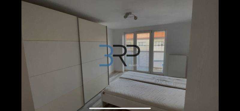 Ein Zimmer in einer 2-Zimmer-Wohnung mit Bett, Einbauschrank und französischem Fenster.