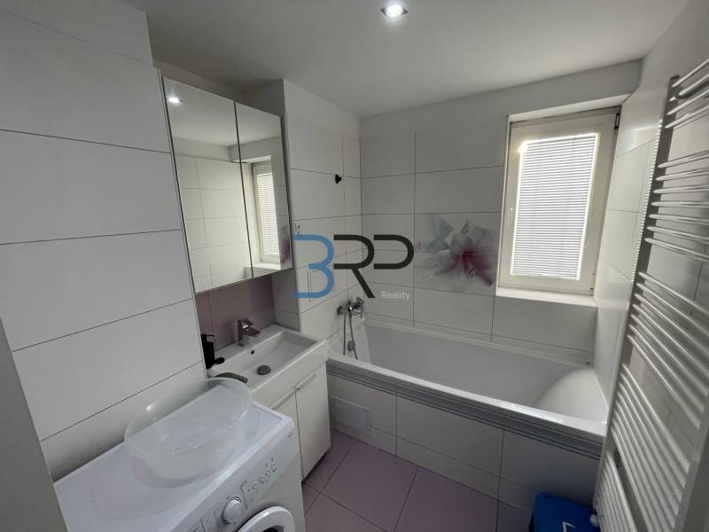 Badezimmer in einer 2-Zimmer-Wohnung mit Badewanne, Waschbecken und Waschmaschine.
