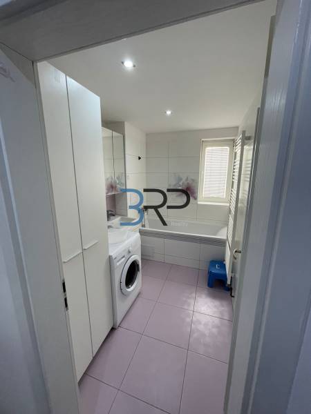 Badezimmer in einer 2-Zimmer-Wohnung mit Waschmaschine, Badewanne, Waschbecken und Stauraum.