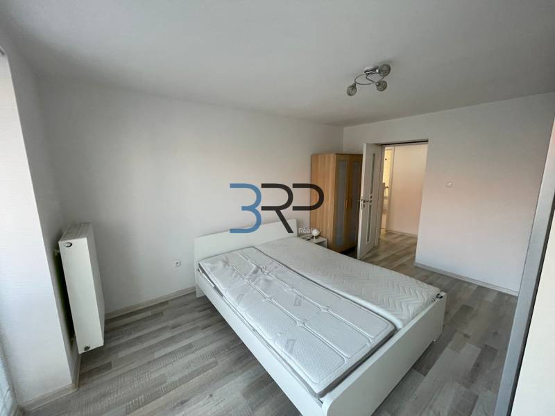 Schlafzimmer in einer 2-Zimmer-Wohnung mit Bett, Schrank und weißen Wänden.