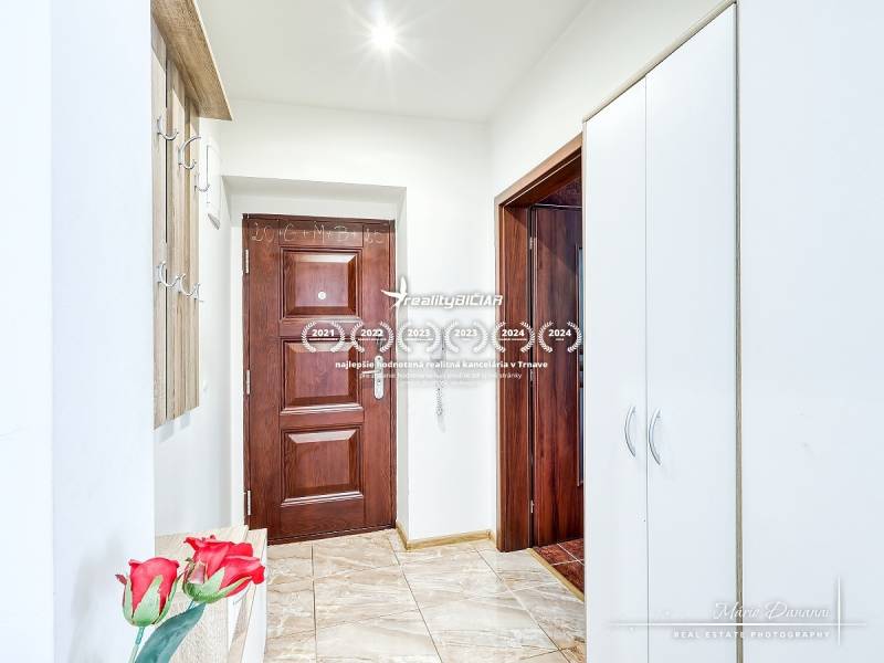 Eingangsbereich einer 2-Zimmer-Wohnung mit Holz- und weißen Schränken und Fliesenboden.