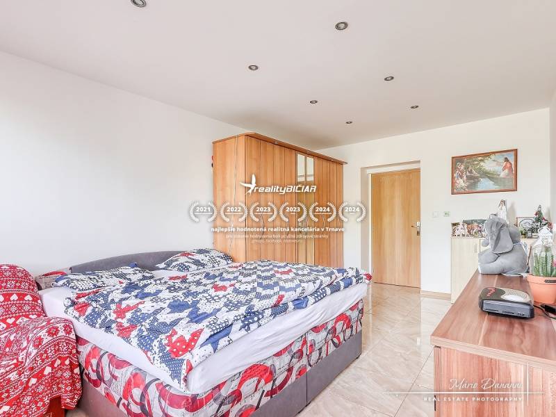 Schlafzimmer in einer 2-Zimmer-Wohnung mit Bett, Schrank und Dekorationen auf der Kommode.