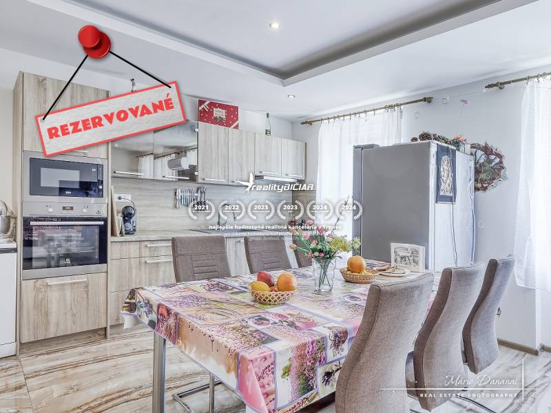 Küche in einer 2-Zimmer-Wohnung mit Tisch, Geräten und dem Schild 