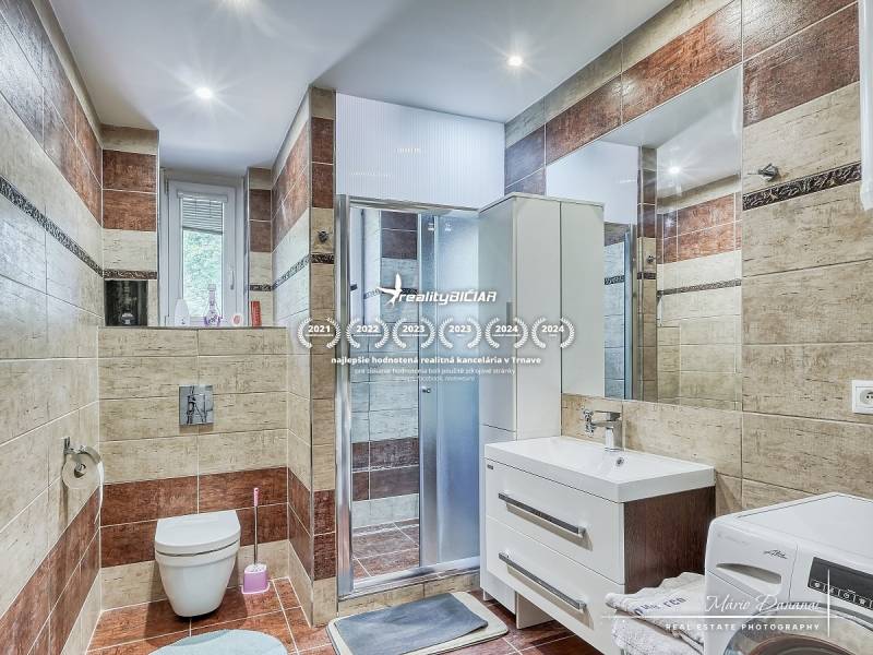 Badezimmer in einer 2-Zimmer-Wohnung mit Fliesen in Braun und Beige.