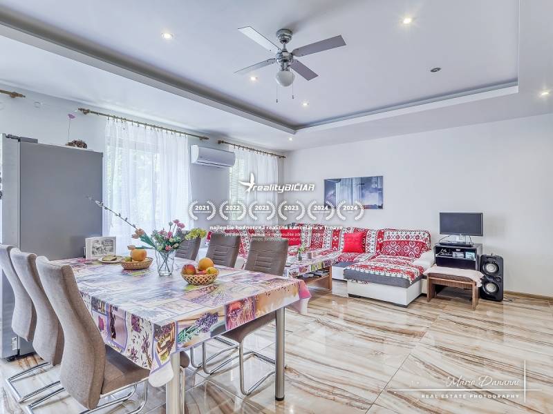 Geräumiges Wohnzimmer mit Esstisch in einer 2-Zimmer-Wohnung, helle Wände und gemustertes Sofa.