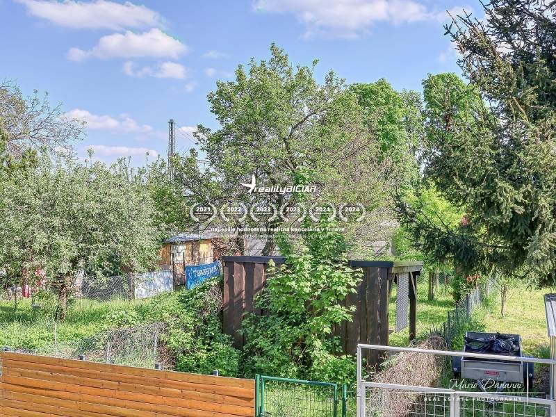 Ein Garten mit einem Holzunterstand, umgeben von Grün, in der Staničná-Straße in Trnava.