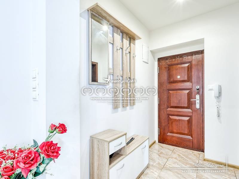 Eingangshalle in einer 2-Zimmer-Wohnung mit Holztüren und Spiegel, dekoriert mit roten Blumen.