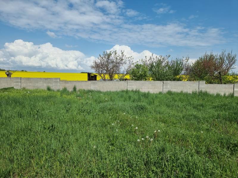 Grünes Grundstück umgeben von einer Mauer mit Blick auf ein gelbes Feld in Cabaj-Čápor. Grundstücke - Wohnen.