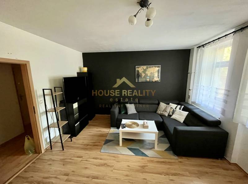 Wohnzimmer in einer Zweizimmerwohnung mit Sofa, Tisch und schwarzer Wand.