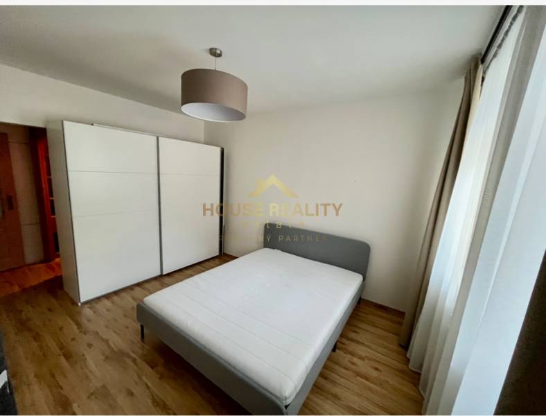 Schlafzimmer in einer 2-Zimmer-Wohnung mit Doppelbett, Einbauschrank und Holzboden.