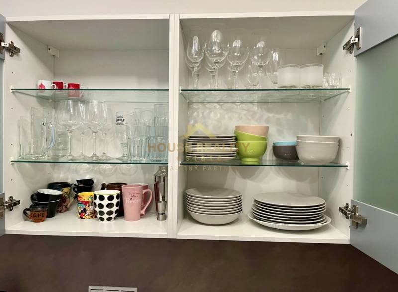 Ein offener Küchenschrank mit Gläsern, Tassen und Tellern in einer 2-Zimmer-Wohnung.