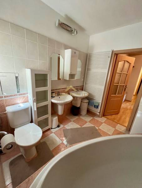 Badezimmer einer Zweizimmerwohnung mit Sanitäranlagen, Schränken und großer Badewanne.