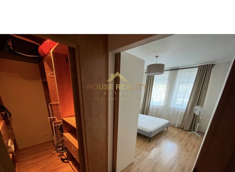 Schlafzimmer in einer 2-Zimmer-Wohnung mit Einbauschrank und Bett, helle Vorhänge.