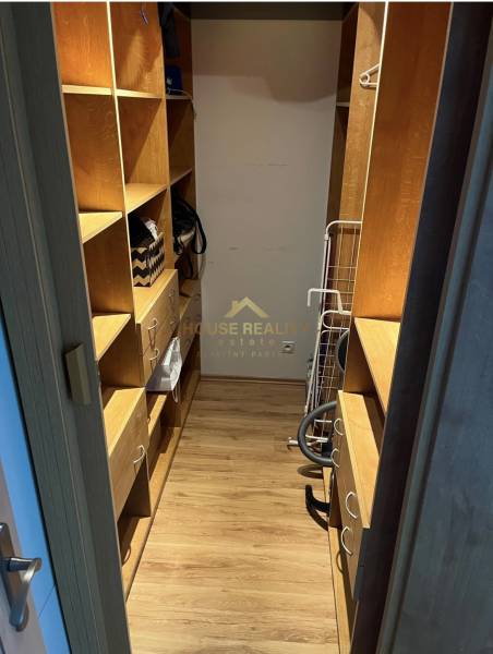 Kleiderschrank in einer 2-Zimmer-Wohnung, Holzregale, praktische Aufbewahrungsmöglichkeiten.