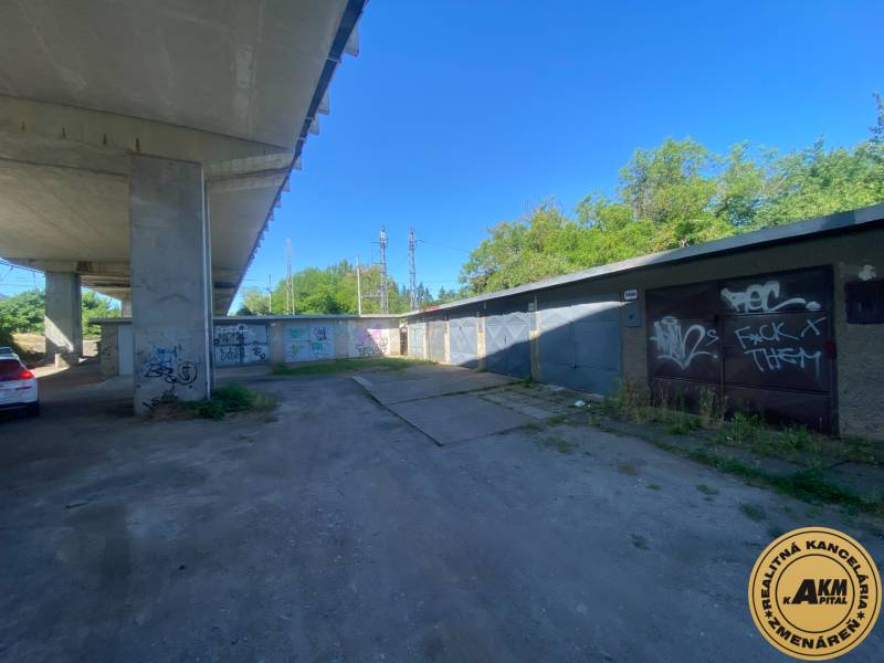 Garagen in Zvolen unter der Brücke mit Graffiti an den Wänden und einem geparkten Auto.