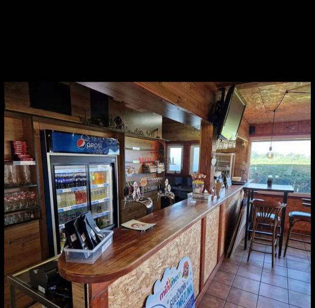 Holzinterieur von Gastronomieräumen mit Bar, Kühlschrank und Fernseher.