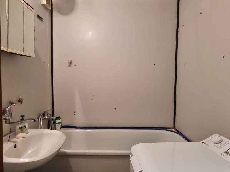 Badezimmer in einer 2-Zimmer-Wohnung mit Badewanne, Waschbecken und Waschmaschine.