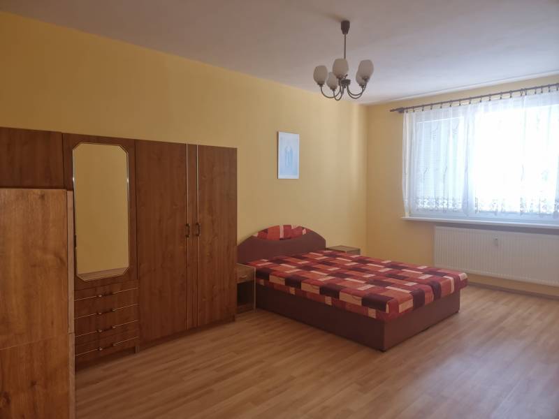 Schlafzimmer in einer 2-Zimmer-Wohnung mit Bett, Kleiderschrank und gelben Wänden.