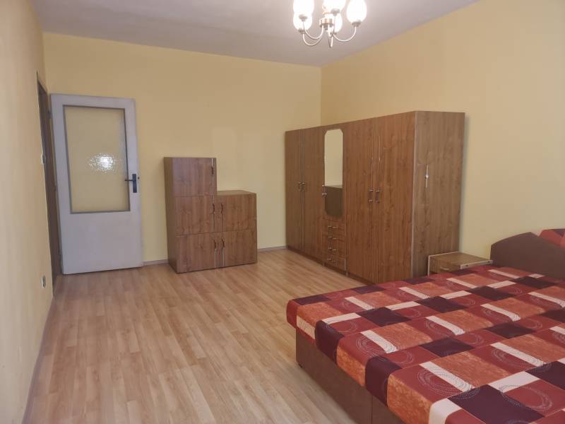 Ein Zimmer in einer 2-Zimmer-Wohnung mit einem Bett, einem Schrank und einer Kommode auf einem Holzboden.