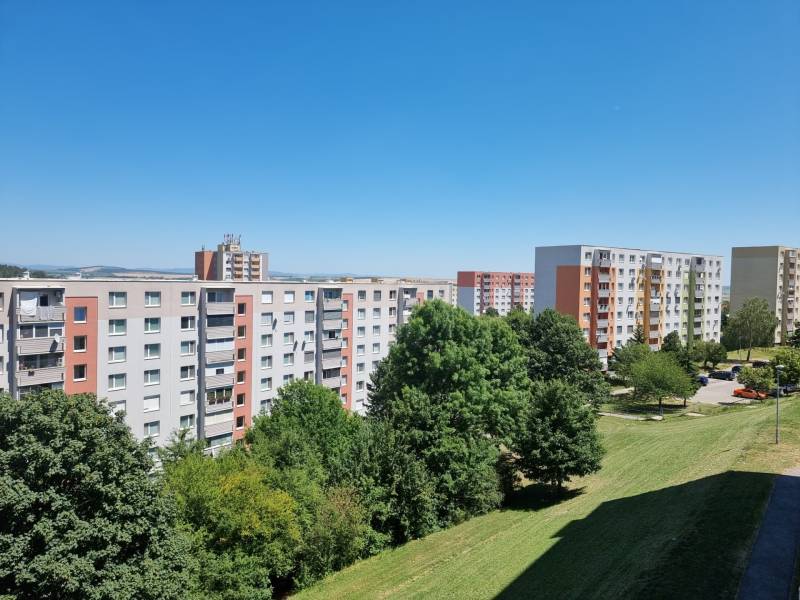 Wohnsiedlung mit Plattenbauten in der Petzwalova-Straße in Nitra, umgeben von Grünflächen und blauem Himmel.