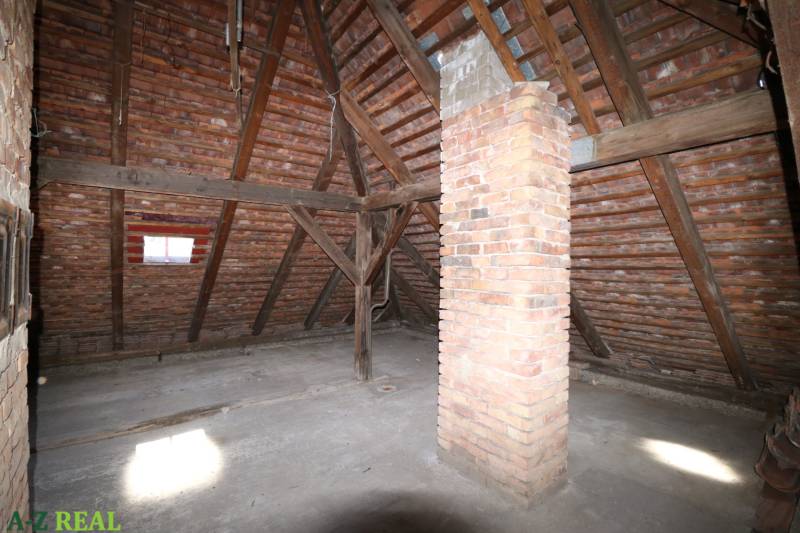 Der Dachboden eines Einfamilienhauses mit einer Holzdachkonstruktion und einem Schornstein aus Ziegeln.