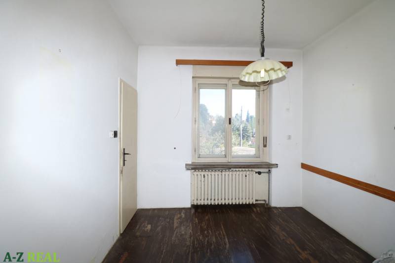 Ein Zimmer mit weißen Wänden, Holzboden, Heizkörper und Fenster in einem Einfamilienhaus.