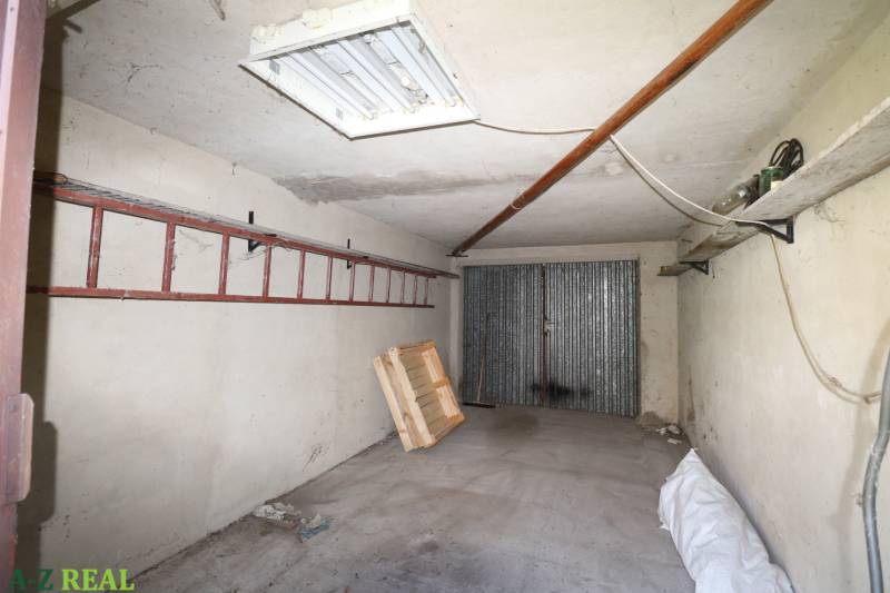 Eine Garage in einem Einfamilienhaus mit einem Garagentor aus Metall, einer Leiter und einer Holzpalette.