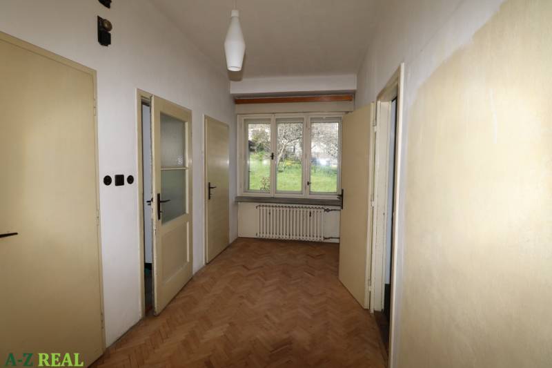 Der Flur in einem Einfamilienhaus mit Holzboden, drei Türen und einem Fenster mit Heizkörper.