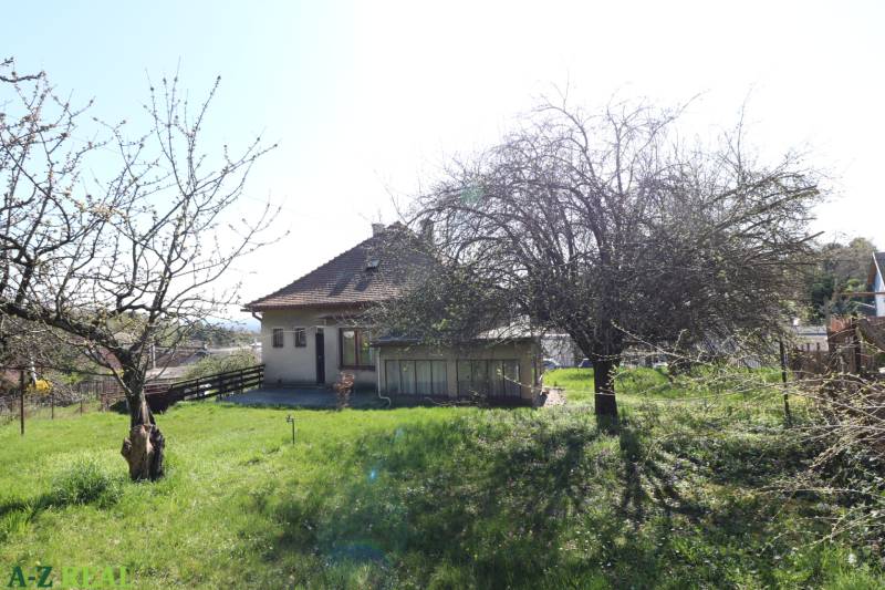 Ein Einfamilienhaus in der Jalovcova-Straße in Bratislava - Koliba mit einem Rasen-Grundstück und Bäumen.
