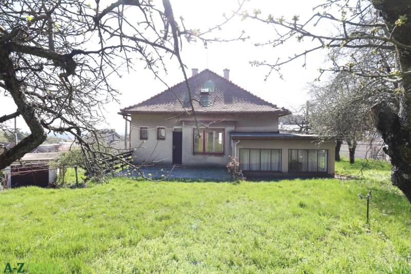 Ein Einfamilienhaus in der Jalovcova-Straße in Bratislava - Koliba, umgeben von einem Garten und Bäumen.