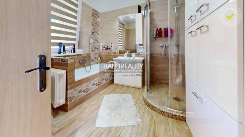 Badezimmer in einem Einfamilienhaus mit Badewanne, Dusche und Waschbecken, warme Holztöne.
