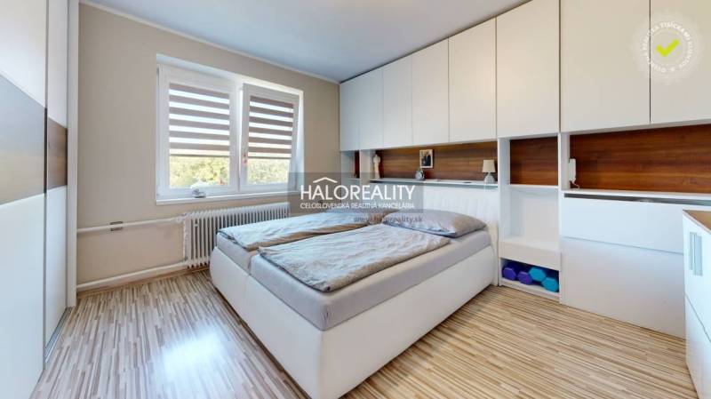 Schlafzimmer im Einfamilienhaus mit großem Bett, Einbauschränken und Fenster.
