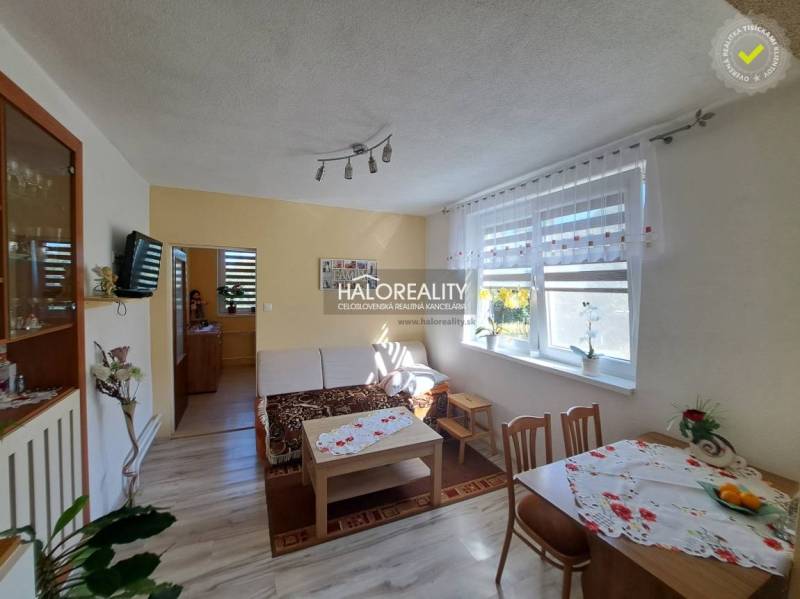 Wohnzimmer in einem Einfamilienhaus mit hellen Vorhängen, einem Holztisch und einem Sofa.