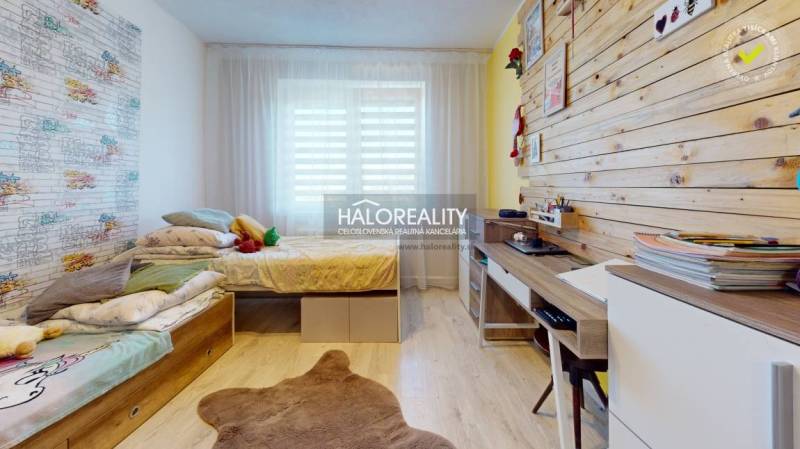 Kinderzimmer in einem Einfamilienhaus mit Holzwand, Bett und Schreibtisch.