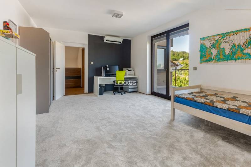 Ein Zimmer in einem Einfamilienhaus mit einem Bett, einem Schreibtisch, einem Balkon und einer Weltkarte an der Wand.