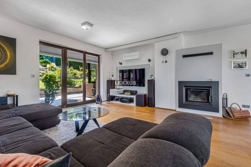 Wohnzimmer mit Kamin, bequemer Couch und verglasten Türen zum Garten in einem Einfamilienhaus.