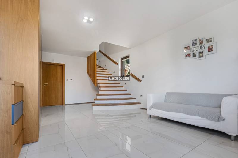Eine Treppe im Einfamilienhaus mit einem Holzgeländer, einem weißen Sofa und Holzmöbeln.