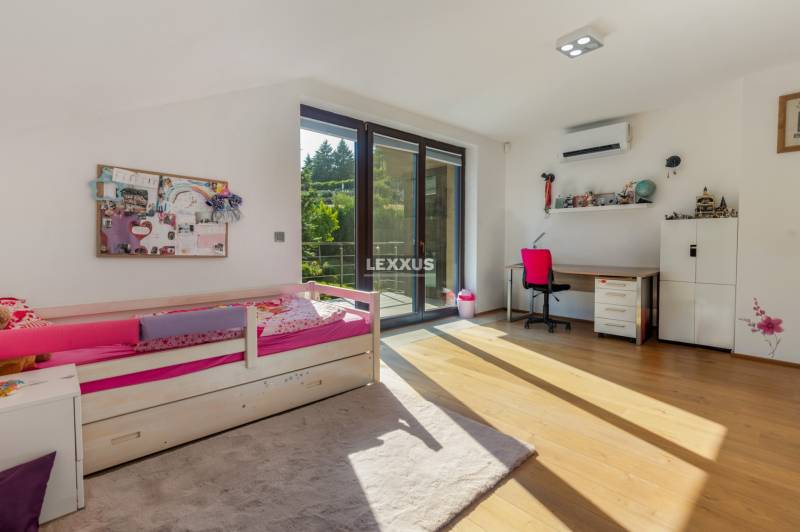 Kinderzimmer in einem Einfamilienhaus mit Bett, Schreibtisch und Balkontür.