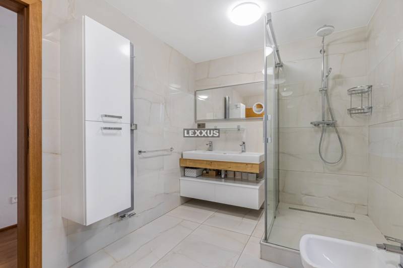 Ein Badezimmer in einem Einfamilienhaus mit einer geräumigen Dusche und einem Waschbecken mit zwei Wasserhähnen.