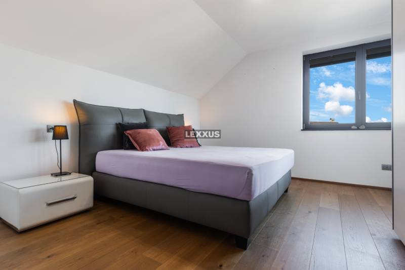 Schlafzimmer im Einfamilienhaus mit großem Bett, Nachttisch und Fenster.