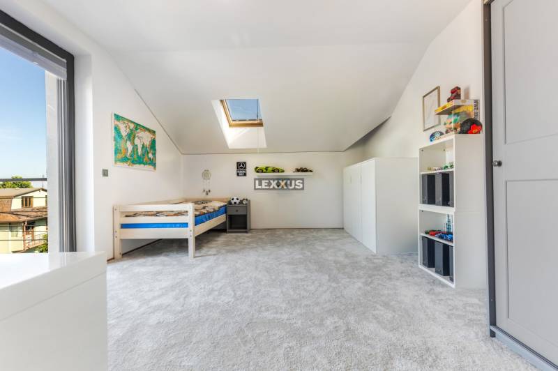 Kinderzimmer im Einfamilienhaus mit Bett, Teppich und Dachfenster.