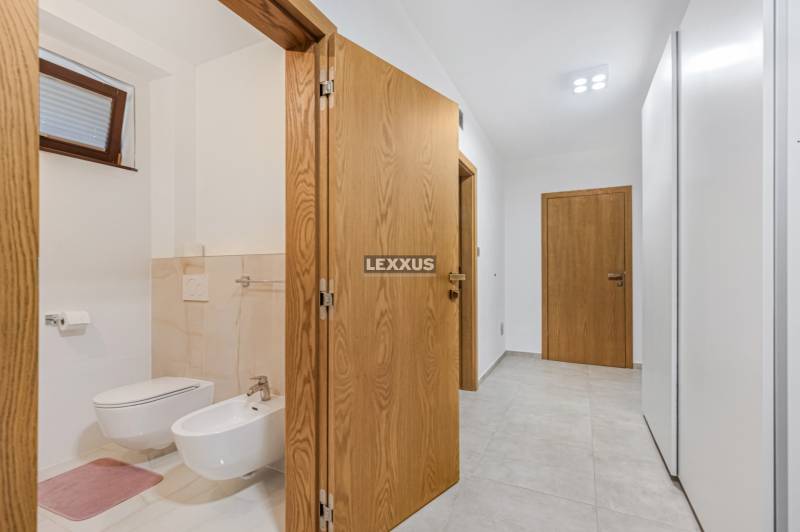 Flur im Einfamilienhaus mit offener Tür zum Badezimmer mit hängendem WC und Bidet.