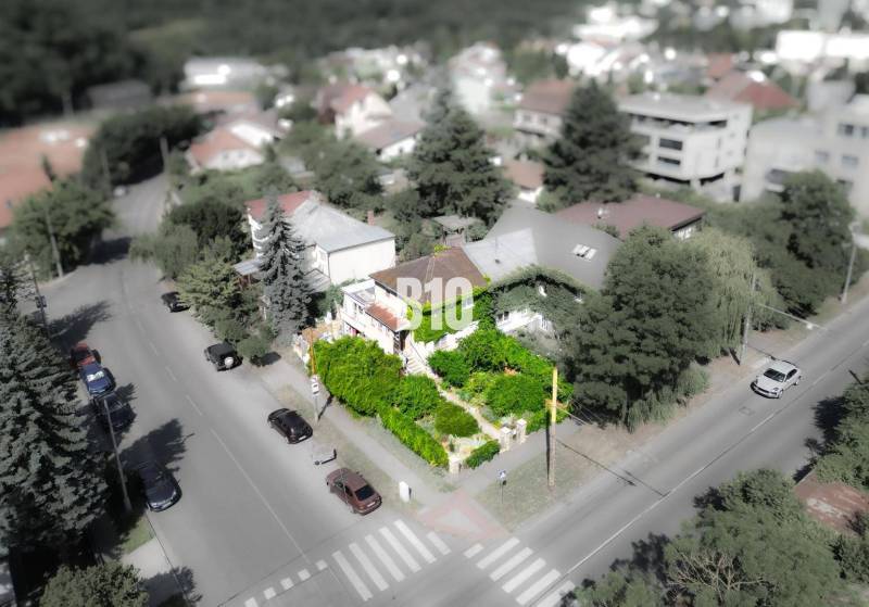 Ein Einfamilienhaus in der Gegend von Bratislava - Altstadt, umgeben von Grünflächen und einer Straße mit Autos.