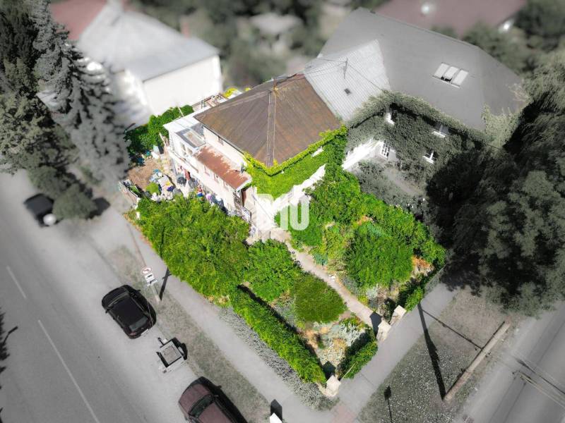 Ein Einfamilienhaus in Bratislava - Staré Mesto, umgeben von dichtem Grün und Bäumen.