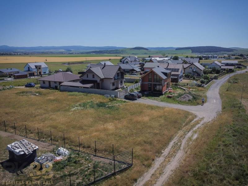 Grundstücke zum Wohnen in Mlynica mit Einfamilienhäusern und ländlicher Landschaft im Hintergrund.